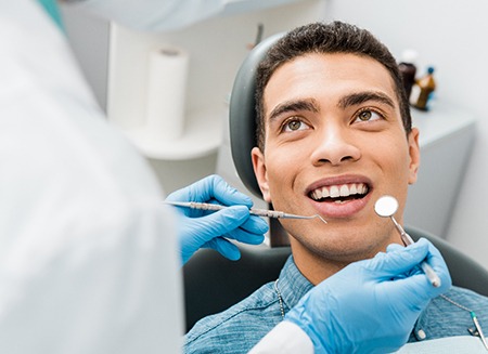 Man in blue shirt sitting in dental chair about to undergo an exam