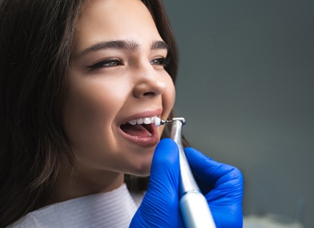 profile view of a woman with brown hair having her teeth polished