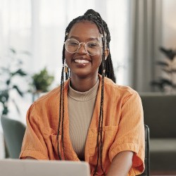 Woman with glasses smiling while working on laptop