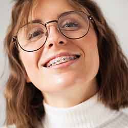 Teen with black glasses and braces smiling