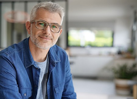 Senior man in denim jacket and glasses smiling